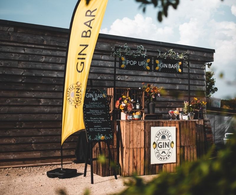 Wooden gin bar with flowers ready at an outdoor event