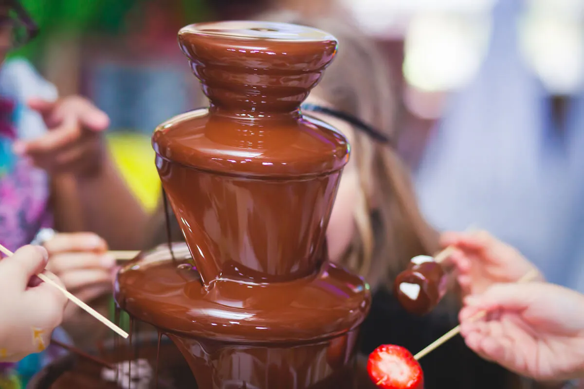Guests covering fruit and marshmallows in chocolate using the chocolate fountain