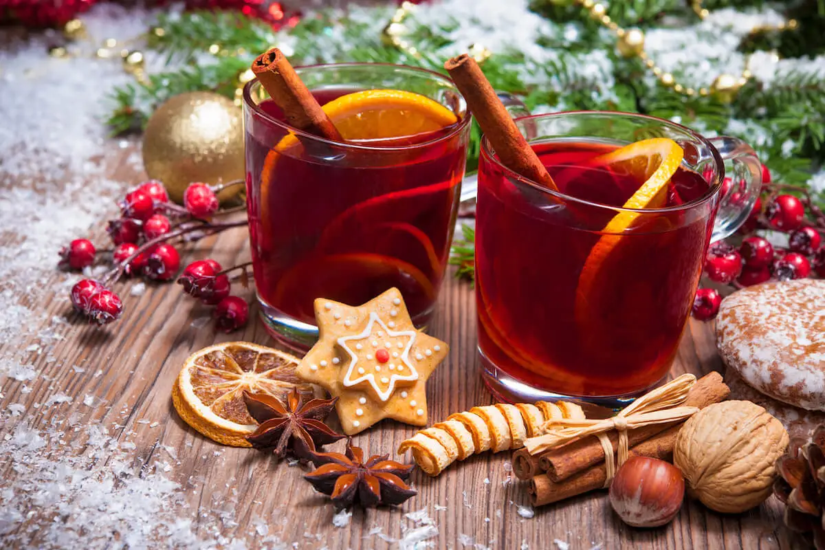 Two glasses of warming mulled wine with slices of orange and cinnamon sticks in a festive backdrop