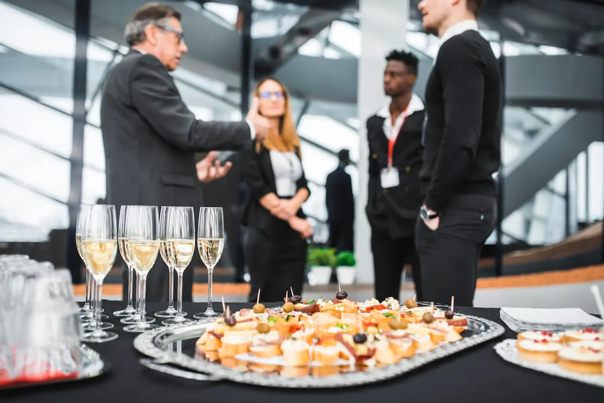 Buffet and canapes at a corporate event with business people in the background