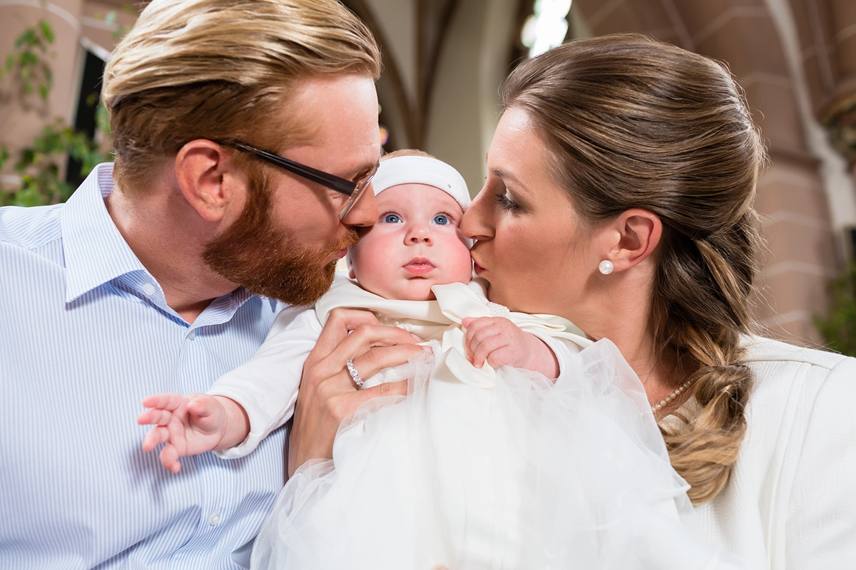 Parents kissing their child after a christening ceremony