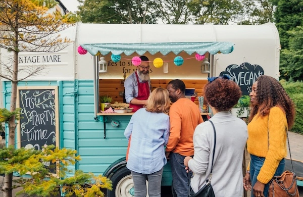 A group of people lined up for a food van at an outdoor event